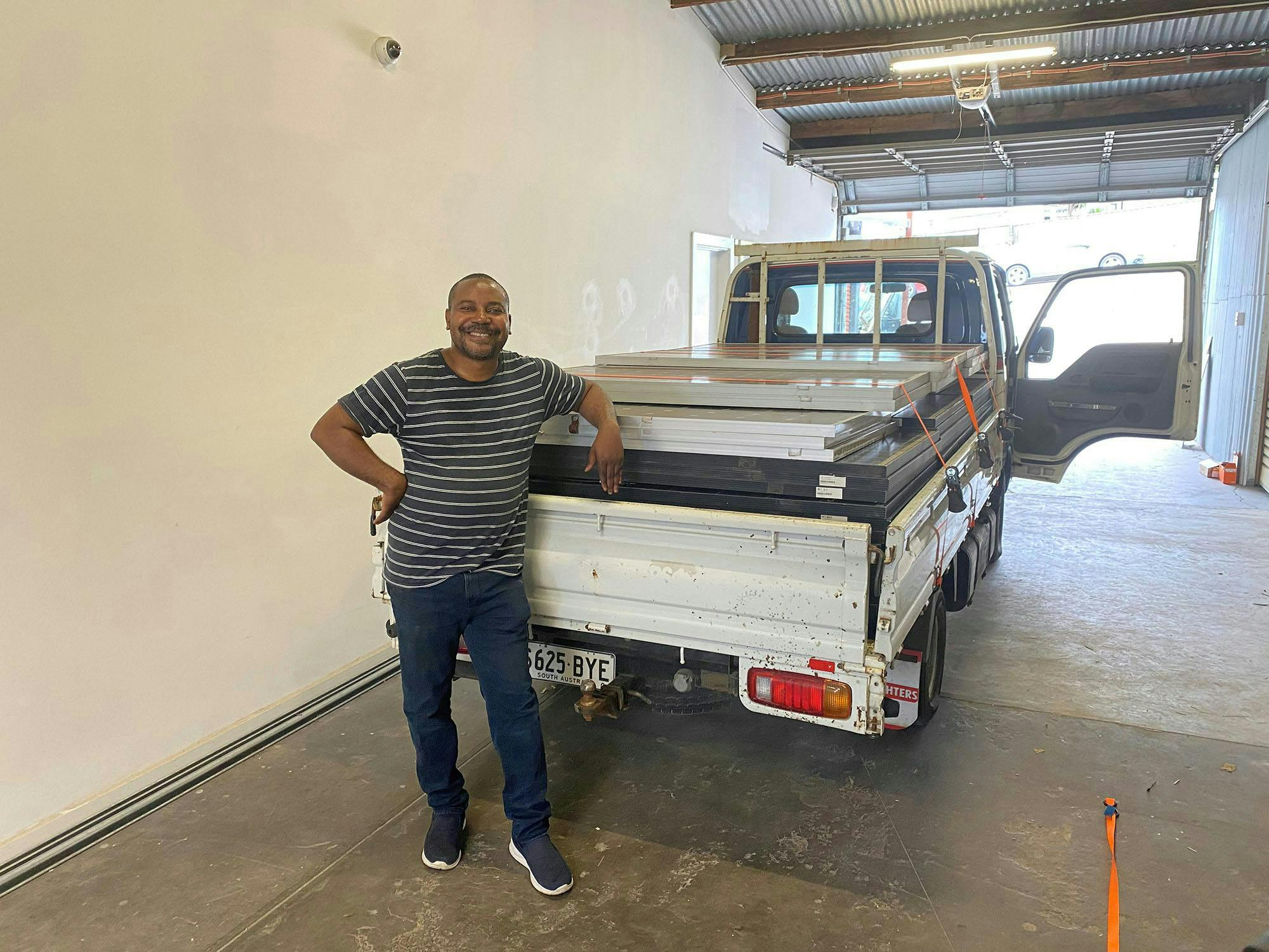 Dr Luc (MHCDASA) smiling with ute full of donated solar panels