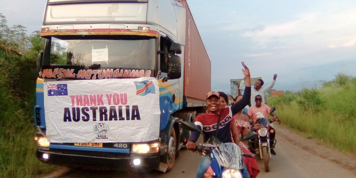 An MHCDASA Container of Hope arriving in DR Congo with locals celebrating on their motorcycles